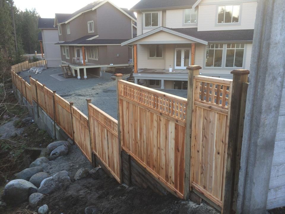 Six-foot western red cedar privacy fence with lattice-top panels stepped along a sloped new-construction property line in the Fraser Valley
