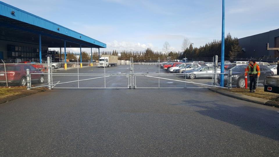Commercial grade galvanized chain link double swing driveway gate with barrier arms — New Westminster, BC commercial project.