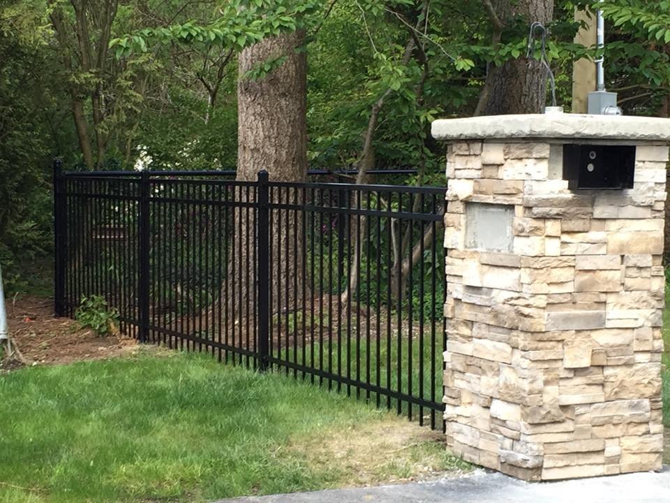 Black powder-coated ornamental steel fence panels next to a stone column in Chilliwack BC