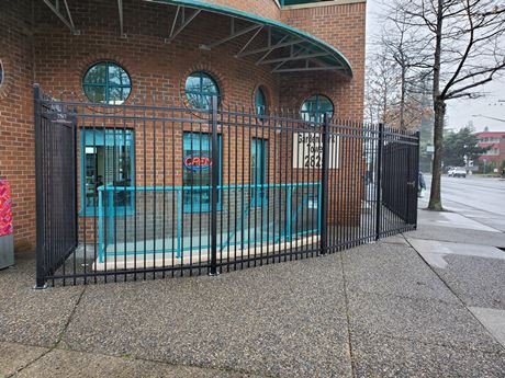 Black powder-coated ornamental steel storefront swing gate outside an Abbotsford commercial building