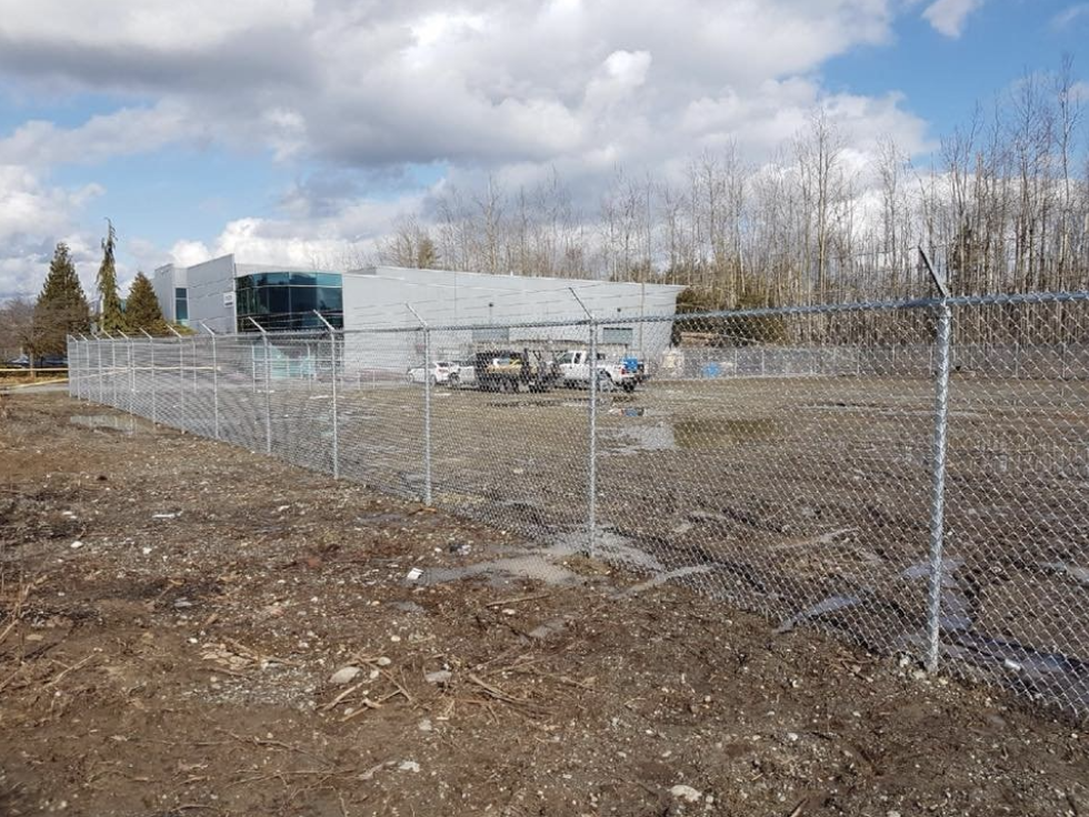 Heavy-gauge galvanized chain link industrial perimeter security fence with three-strand barbed wire topping in Langley, BC.