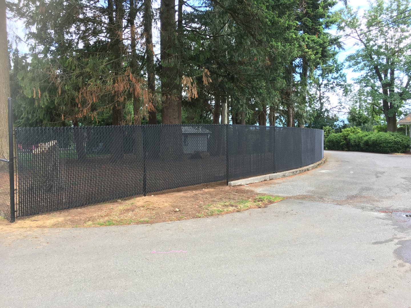 Black chain-link fence with privacy slats beside a driveway — photograph supplied by LS Fencing & Metal Work
