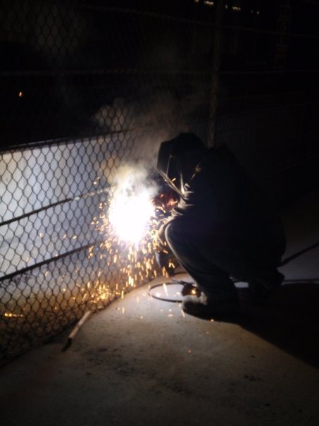 On-site welding at a chain-link fence — photograph supplied by LS Fencing & Metal Work